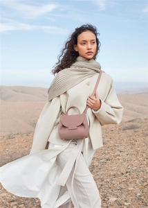 Chic pink leather shoulder bag with flap and handle shown in a professional outdoor setting