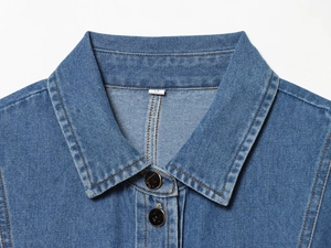Detailansicht eines blauen Denim-Hemdkragens mit gelben Nähten und Metallknöpfen