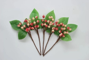 Detail of five artificial winterberry branches with red and white berries and green leaves
