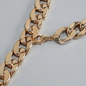 Detail of chunky gold chain link necklace featuring a secure lobster clasp closure