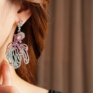 Détail de boucles d'oreilles poisson vintage avec pierres mauves et perles bleues