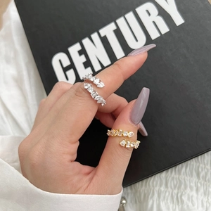 Detail view of gold and silver open rings with geometric zircon stones on a model's hand