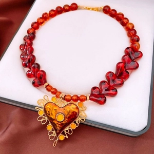 Macro view of vintage heart pendant necklace with gold filigree and red heart-shaped beads