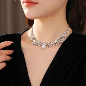 Close-up of a silver necklace featuring a pink pear-shaped stone and rhinestone details