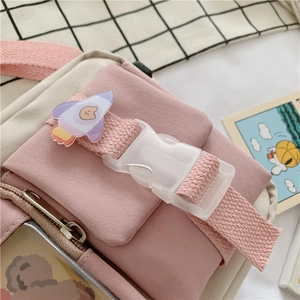Close-up of pink canvas shoulder bag featuring a cute bear badge and a durable plastic buckle