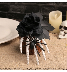 Detail of Halloween hair clip with black rose, skeleton hand and spider on a rustic stand