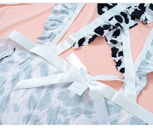 Detail of cow print lingerie with white satin bow and ruffle trim on pink fabric