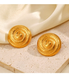 Détail macro de boucles d'oreilles dorées avec texture spirale sur pierre