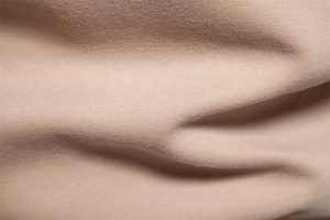 Macro shot of soft breathable light beige knitted cotton fabric with fine texture