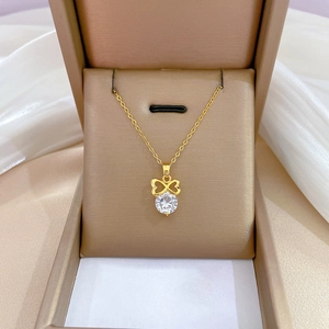 Macro shot of a gold-plated bowknot pendant with a large claw-set white zircon in a gift box