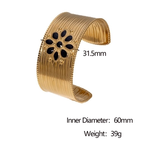 Detailed view of wide 18k gold plated stainless steel bangle with sun symbol and black petals