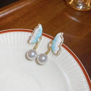 Détail de boucles d'oreilles papillon avec ailes dégradées, zircon et perle blanche