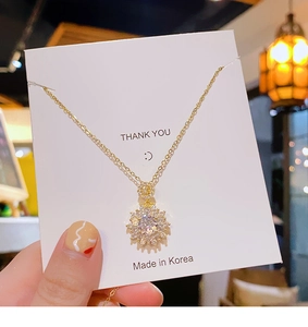 Detail shot of a luxury gold sunflower pendant necklace with sparkling pavé zircons