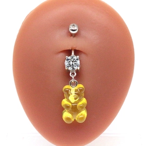 Macro shot of silver navel ring featuring a yellow candy bear and clear cubic zirconia