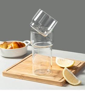 Close-up of stackable borosilicate glass cups with lemon and bread on a rustic table