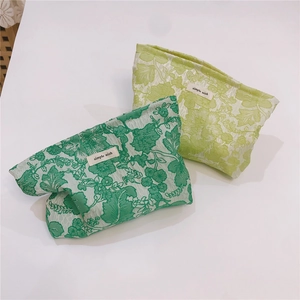 Detail of green floral jacquard canvas makeup bags with a textured finish and logo