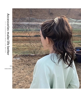 Outdoor model shot of beige bird nest hair clip and golden twisted hoop earrings