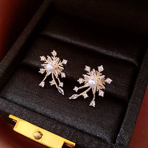 Vue détaillée de boucles d'oreilles flocon avec perle et cristaux en écrin de velours