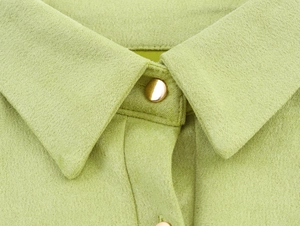 Detail eines hellgrünen Wildleder-Hemdkragens mit goldenem Knopf und feinen Nähten