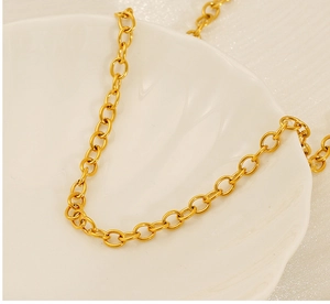 Close-up of golden stainless steel oval link chain necklace on a white ceramic tray