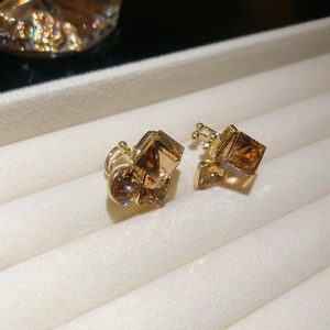Macro shot of gold plated earrings featuring amber crystals on velvet display tray