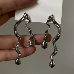 Detailed close-up of asymmetric twisted silver snake drop earrings with water drop charms