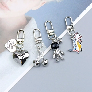 Detail view of silver astronaut, cherry, heart and dinosaur alloy keychain charms