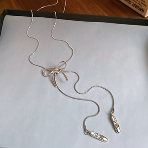 Detailed view of silver snake chain with bow charm and ballet slipper pendants
