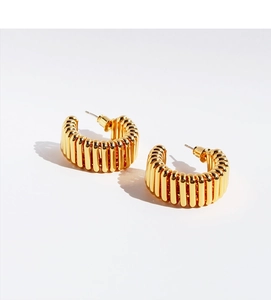 Close-up of golden C-shaped hoop earrings featuring vertical ribbed texture and glossy finish