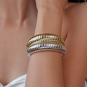 Detailed close-up of ribbed metallic bangles in polished gold and silver finishes