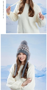 Détail du bonnet en maille grise avec pompon et protège-oreilles sur fond de neige