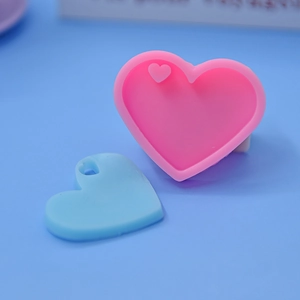 Detail of pink heart silicone mold with a blue DIY heart pendant showing relief texture