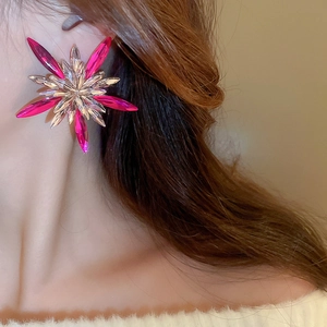 Detailed close-up of oversized star earrings featuring fuchsia and clear crystal starburst
