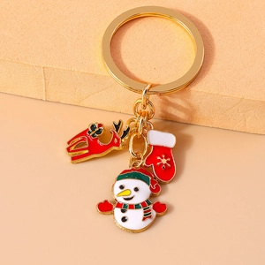 Detail of Christmas keychain with gold ring featuring enamel reindeer, snowman and mitten charms