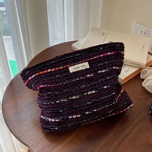 Detail of wool tweed cosmetic bag with colorful patterns and Simple Wish label on wood