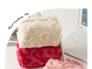 Detailed view of plush makeup bags with embossed heart patterns in three soft colors