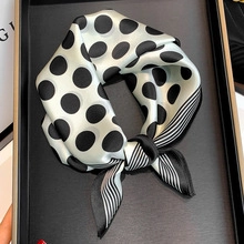 Close-up of silk-like square scarf with classic black polka dots and striped border details