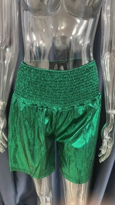 Detail of high-waisted green metallic shorts with elastic waistband on a model