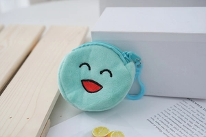 Detailed close-up of a mint green plush emoji coin purse with blue plastic hook and zipper