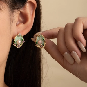 Detail of vintage French floral earrings with green enamel and a pink pearl accent