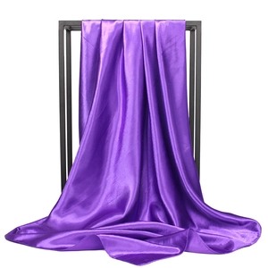 Close-up of bright purple silk satin headscarf draped over a black metal display frame