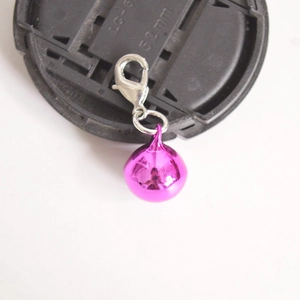 Macro shot of rose red metal round bell charm with a silver lobster clasp attachment