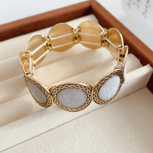 Detail of vintage gold textured oval link bracelet with grey enamel double C relief logo