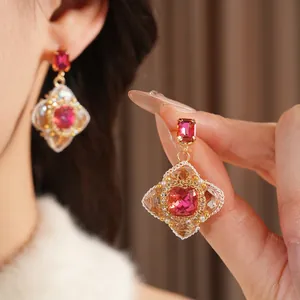 Vintage style gold earrings with pink gemstones and white bead details on a model
