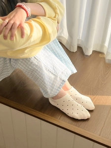 Vue détaillée de chaussettes beiges en coton à pois noirs sur parquet en bois