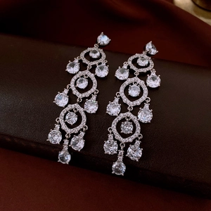Macro shot of silver tassel earrings with round cubic zirconia on a dark leather base
