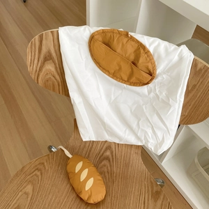 Detailed view of bread-shaped accessory and foldable tote bag on a wooden seat