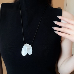 Close-up of textured irregular geometric metal pendant on a black leather cord necklace