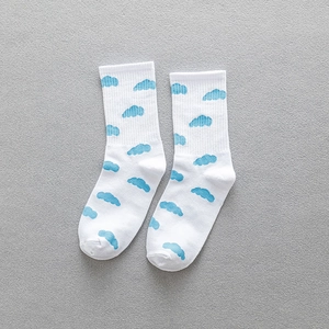 Mid-cut white cotton socks with blue cloud patterns on a textured grey fabric surface