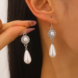 Dettaglio di eleganti orecchini a goccia in argento con perle e strass brillanti su modella